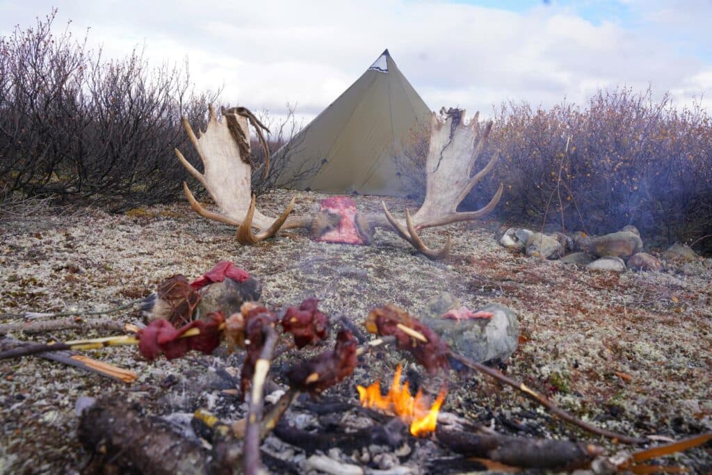 Subsistence camp with fire, drying meat, and moose antlers